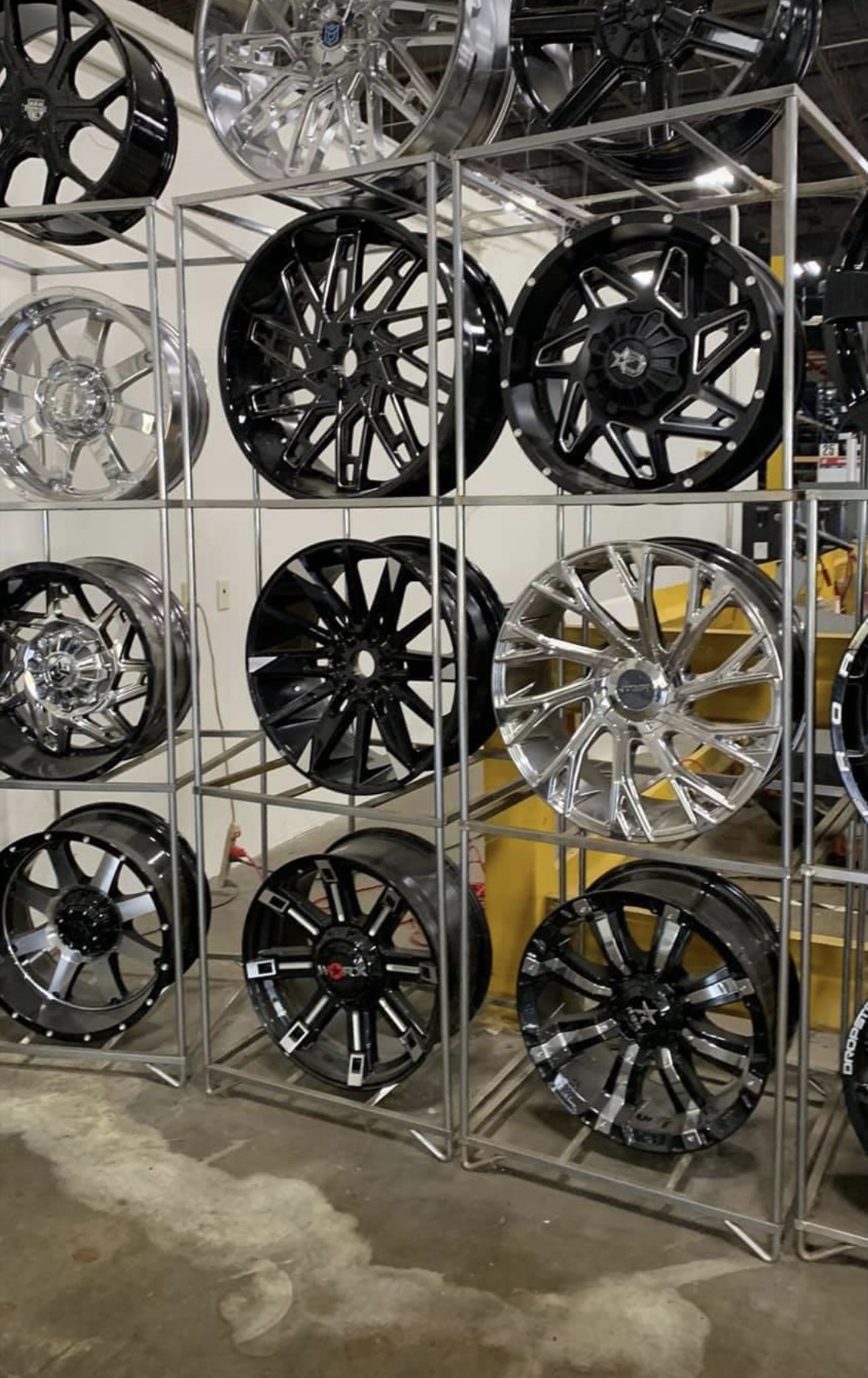 Black, chrome, and machined rims displayed on racks